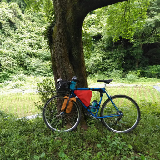 キャンプツーリング装備の自転車と里山の写真