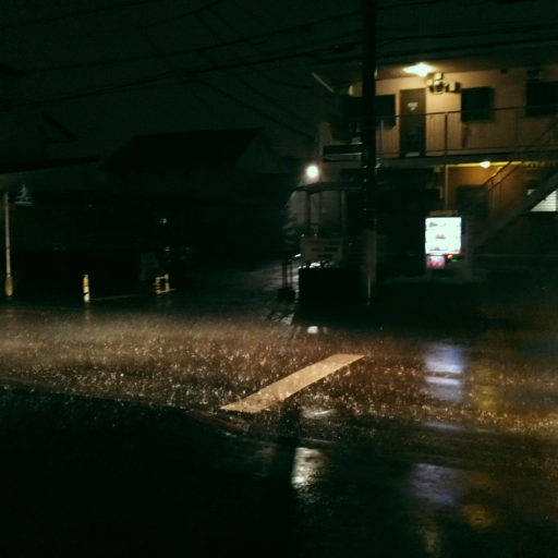 強い雨が夜の道路を叩いている様子
