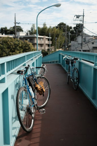 歩道橋の平坦部分のフェンス、左右それぞれの側に立てかけられた計2台の自転車の写真