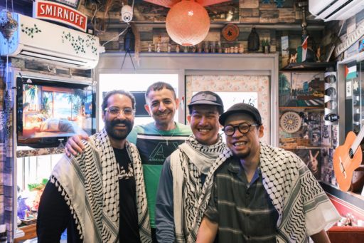 ビサン店内で撮影された集合写真。左からベトさん、マンスールさん、筆者、Hideさん。マンスールさん以外は首や肩にクーフィーヤを掛けている。全員笑顔でこちらを向いている。