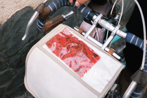 ベトさんの自転車に付いているフロントバッグ。トップが透明のビニール素材になっており、「We Are All Palestinians」とプリントされた赤い布パッチが中に入っている。