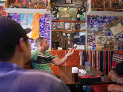 ビサン店内で、手に持ったポーチをしげしげと眺めているマンスールさん。緑色のTシャツに、髪型はトップを少し残した坊主頭。