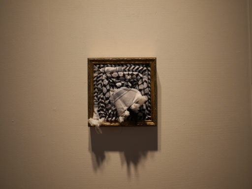 パレスチナの伝統的なスカーフ「クーフィーヤ」を額縁に敷き詰めた作品が壁に掛かっている。