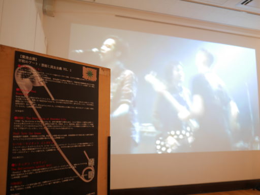 白い壁面に映画が投影されている。手前には作品解説ボード。