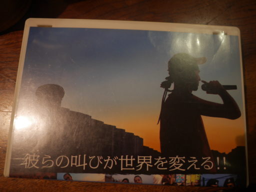 『自由と壁とヒップホップ』のフライヤーの上半分。「彼らの叫びが世界を変える！！」というコピーの背景に、夕焼け空をバックにマイクを構えるラッパーの姿がある。
